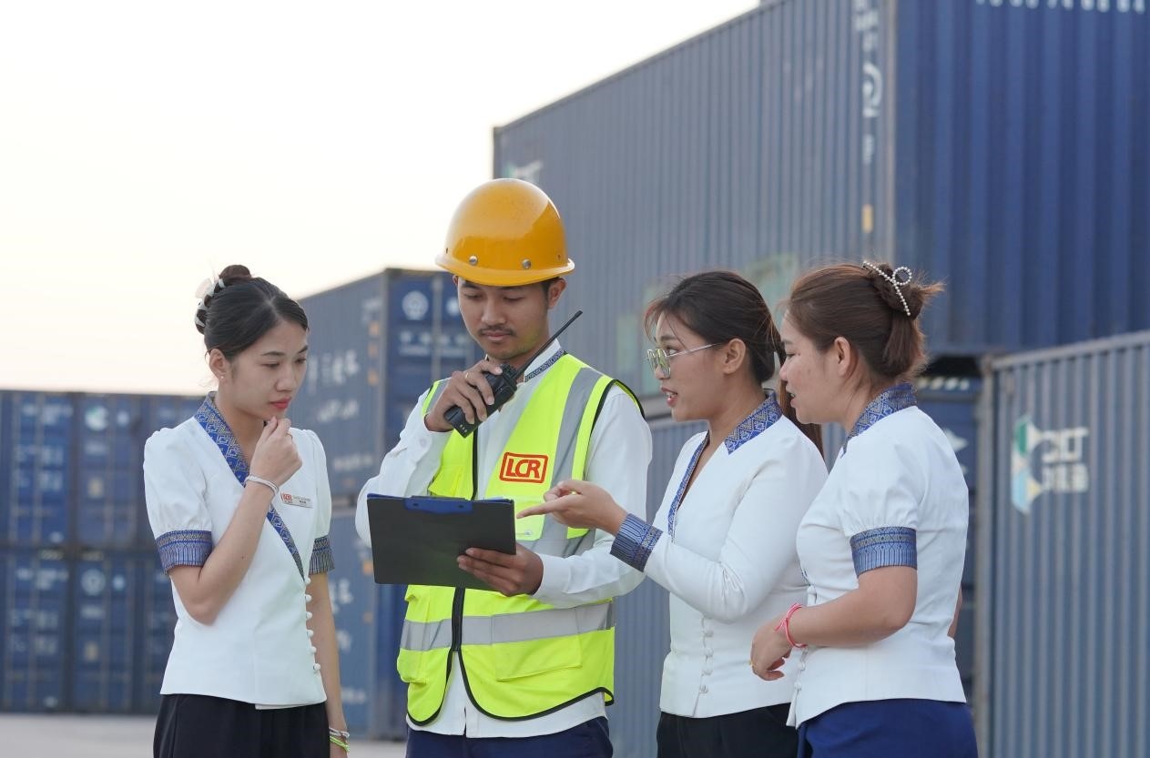 萬象南站貨運值班員陳尼啦（左一）與同事在一起討論工作。老中鐵路有限公司供圖