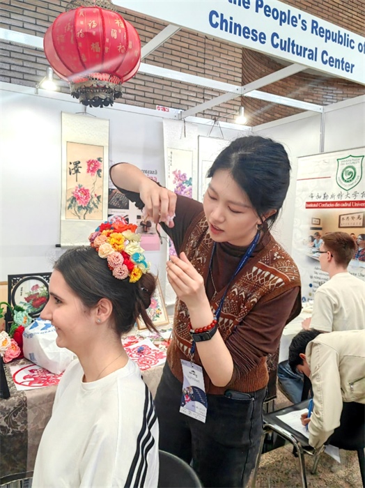 展覽正值羅馬尼亞迎春花節(jié)，國際中文教師志愿者潘婧穎向游客們介紹了國家非物質(zhì)文化遺產(chǎn)——福建泉州的簪花文化。布加勒斯特大學孔子學院供圖。