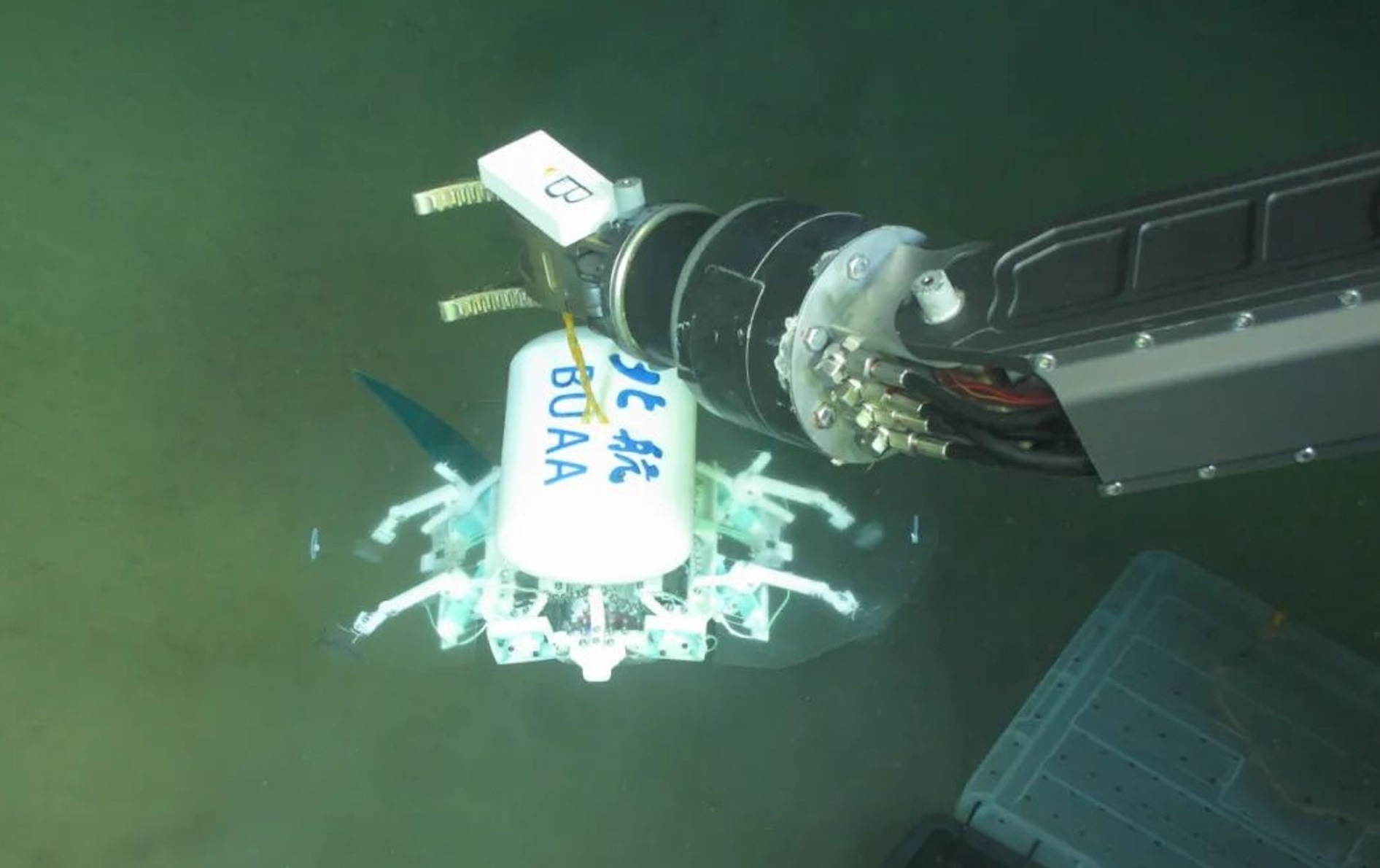 科研人員利用機械臂將北航深海小型機器人投于馬里亞納海溝。校方供圖