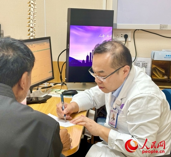 路桂軍接診時(shí)為患者寫下用藥提示。人民網(wǎng)記者 金慧慧攝