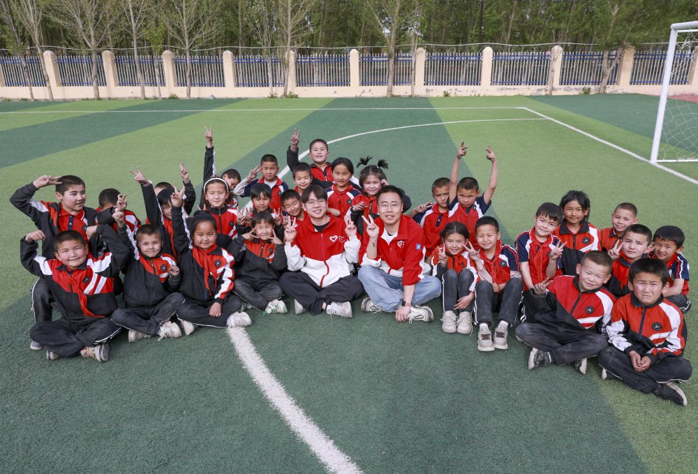 4月23日，在新疆克州阿圖什市哈拉峻鄉(xiāng)謝依特小學(xué)，支教教師王俊文（中左）、李軻凡（中右）和學(xué)生在一起。