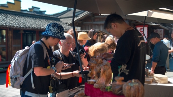 “五一”期間，游客正在烏鎮(zhèn)“水鄉(xiāng)碼頭”挑選購買文創(chuàng)產(chǎn)品。受訪者供圖